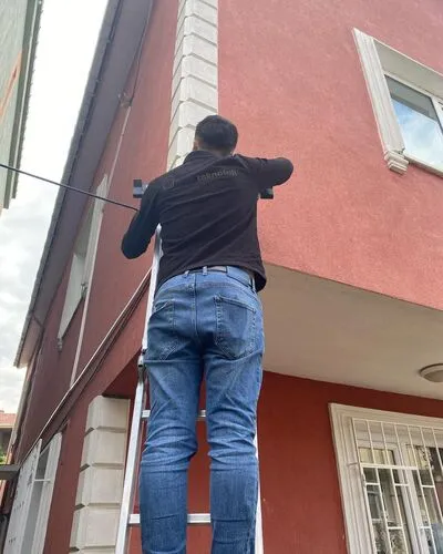 Bina dış cephesinde kamera montajı yapan teknisyen